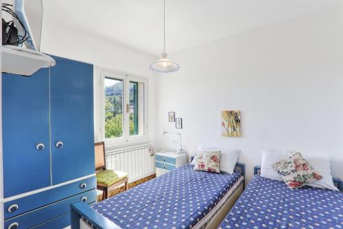 a bedroom with two beds and a blue cabinet at Il giardino nel sole Trilo in Capoliveri