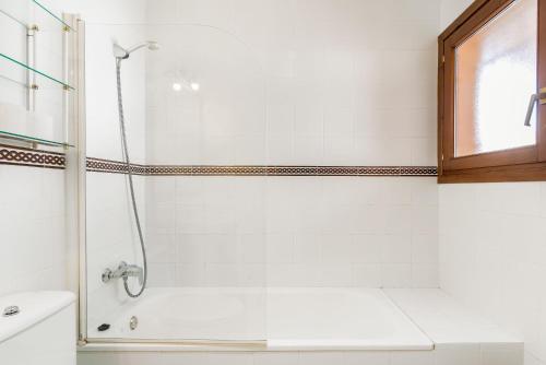 a white bathroom with a shower and a sink at Apartamento La Caracola in Chiclana de la Frontera