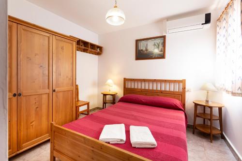 a bedroom with a red bed with two towels on it at Sa Caseta in Llubí
