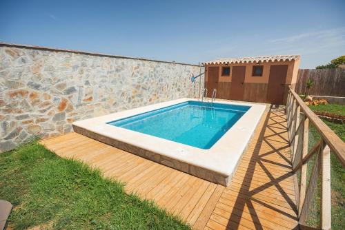 a swimming pool on a deck with a stone wall at Imasaru in Roche