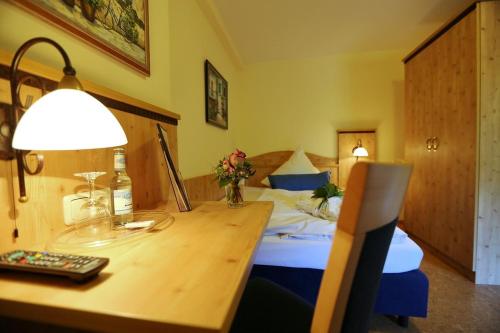 a hotel room with a bed and a desk with a lamp at Landhotel Villa Moritz garni in Oberahr