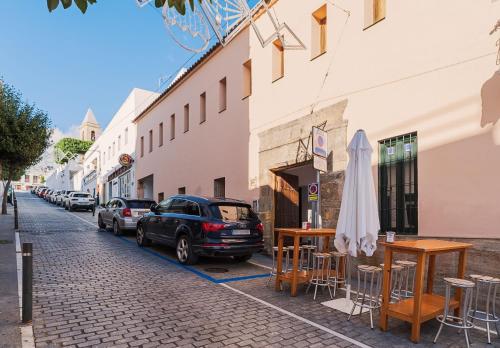a street with tables and chairs and a car parked next to a building at La Tahona de Max&jan in Conil de la Frontera