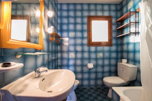 een blauw betegelde badkamer met een wastafel en een toilet bij Villa Belvedere 76 in Son Bou