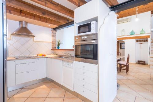 a kitchen with white cabinets and a stove at Sa Fusteria in Sóller