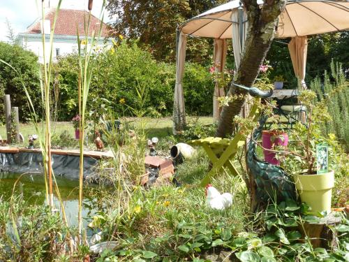 a garden with a pond and an umbrella and chickens at Le Ch'tipanier in Morcenx