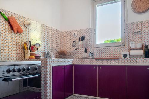 una cucina con armadietti viola e una finestra di Il Grifo - Cozy house, wonderful view a Portoferraio