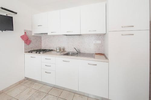 a kitchen with white cabinets and a sink at Villa Belvedere Nisporto in Nisporto