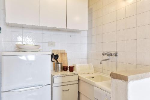 una cucina bianca con frigorifero e lavandino di Studio La Gorgona a Zanca