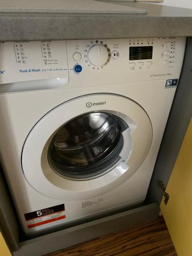 a white washing machine sitting under a counter at APARTMENT A&D CENTRUM in Poprad