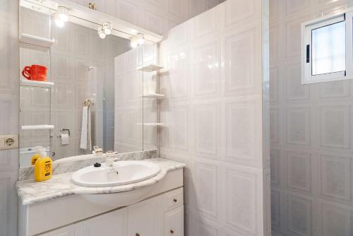 a white bathroom with a sink and a mirror at Casa - 4 Mar y Arena in Barbate