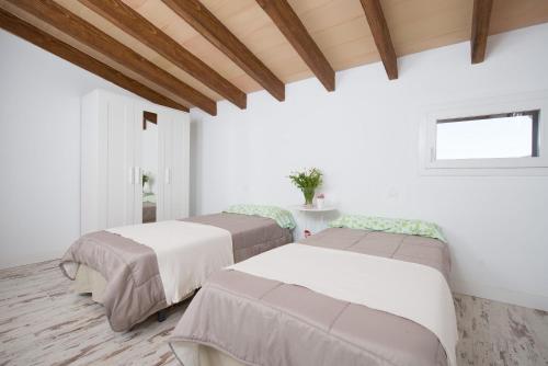 2 Betten in einem Zimmer mit weißen Wänden und einem Fenster in der Unterkunft Can Ferrer in Alcúdia