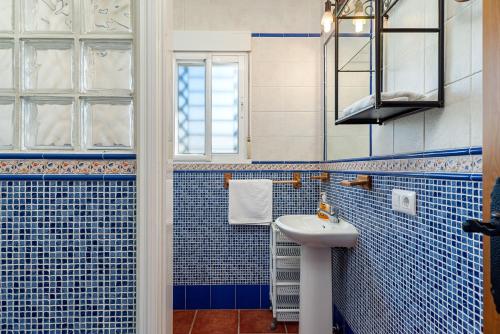 ein blau gefliestes Bad mit einem Waschbecken und einem Fenster in der Unterkunft Casa 3 - Mar y Sol in Barbate
