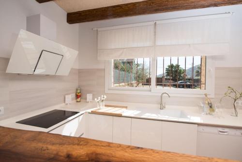 eine weiße Küche mit einem Waschbecken und einem Fenster in der Unterkunft Can Ferrer in Alcúdia