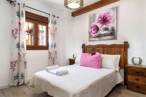 Un dormitorio con una cama blanca con almohadas rosas. en Casa El Duque, en Vejer de la Frontera