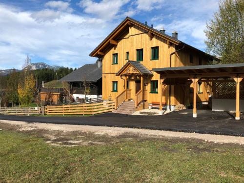 a large wooden house with a porch and a fence at Ausseer Chalet (nahe Hallstatt), Appartements in Bad Aussee
