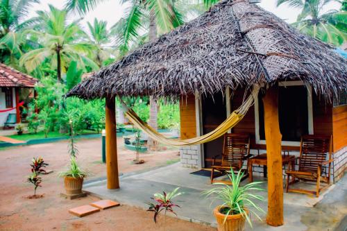 a hut with a hammock and chairs and palm trees at Star Light Cabanas & Restaurant in Tangalle