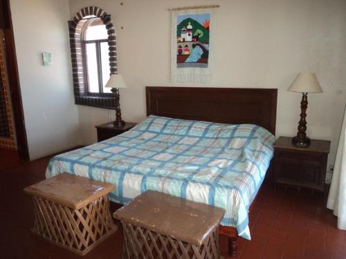 a bedroom with a bed and two tables and a window at La Casa Contenta in Mazatlán