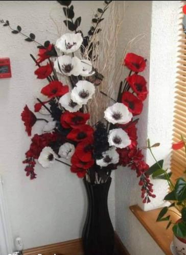 a black vase filled with red and white flowers at Clare Street B&B in Nenagh