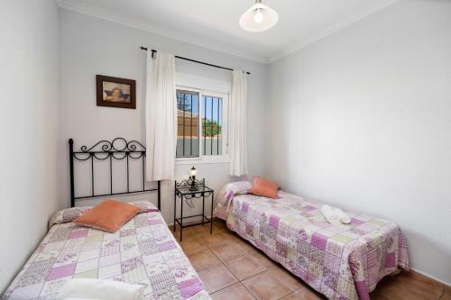 two beds in a room with a window at Chalet Isla del Sotillo in Chiclana de la Frontera