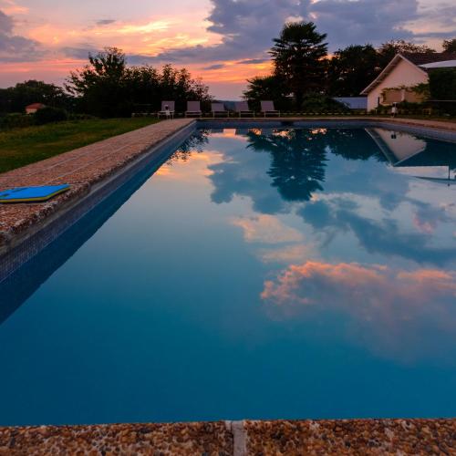a swimming pool with a cloudy sky in the sky at Clos Mirabel Manor - B&B in Jurançon