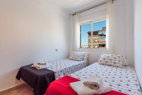 Duas camas num pequeno quarto com uma janela em Apartamento Mariam em Málaga