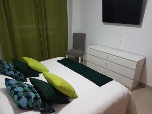 a bedroom with a bed with green pillows and a television at J&E Flat Santa Cruz de la Palma in Santa Cruz de la Palma