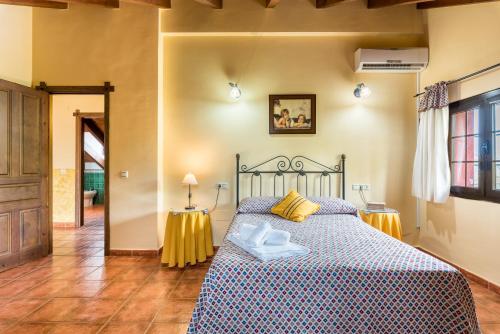 a bedroom with a bed with a blue and yellow bedspread at Casa Rural Loma El Letrao in Almogía