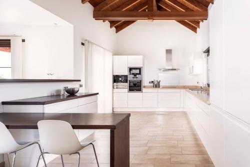 a kitchen with a wooden table and white chairs at Villa Annunaki in Lajares