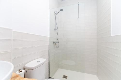 a white bathroom with a shower and a toilet at Apartamento Luna in Barbate