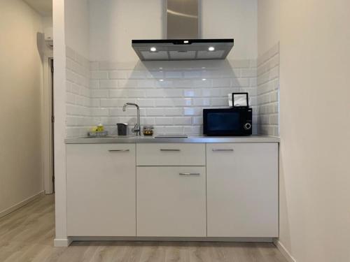 a white kitchen with a sink and a microwave at City Heart Place 1 in Porto