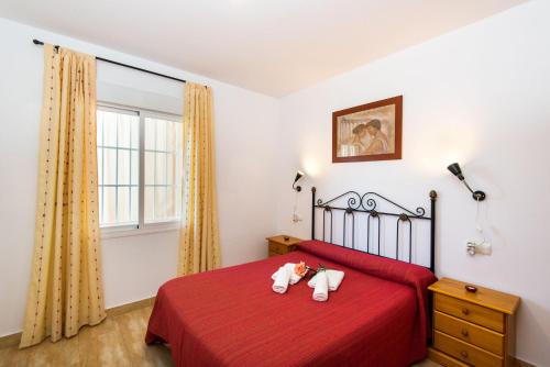 - une chambre dotée d'un lit rouge avec deux animaux rembourrés dans l'établissement Apartamento Rural De Oses 1, à Totalán