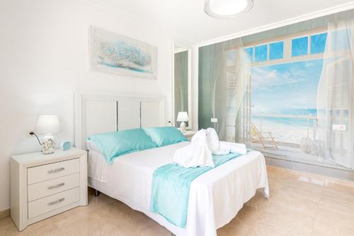 ein weißes Schlafzimmer mit einem Bett und Meerblick in der Unterkunft Villa Felicidad destino romántico in Sayalonga