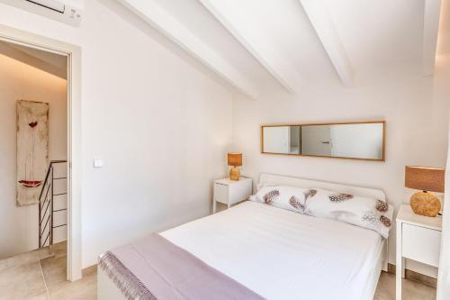Un dormitorio blanco con una cama y un espejo. en Sos Fuyes, en Artà