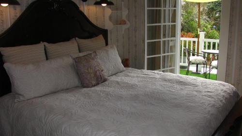 a bed with white sheets and pillows in a bedroom at Terraluna Inn in Roseburg