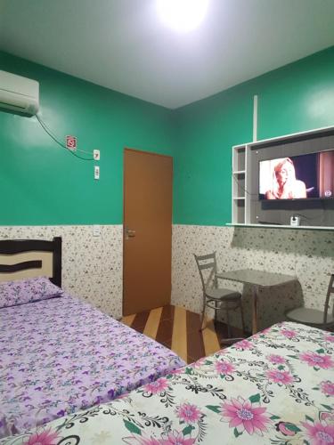 a bedroom with two beds and a flat screen tv at Pousada Pouso Feliz in Fortaleza