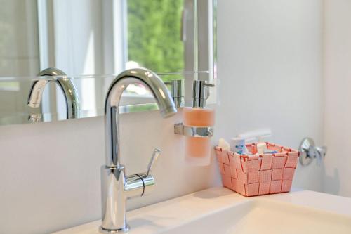 a sink with a faucet and a basket of toothpaste at Fewo Trudi in Grabenstätt