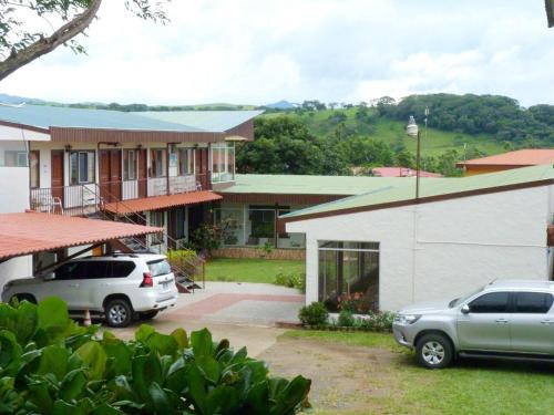 dos autos estacionados frente a una casa en Hotel Naralit, en Tilarán