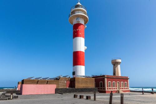 a red and white lighthouse on the beach at Casa Orymar in Cotillo
