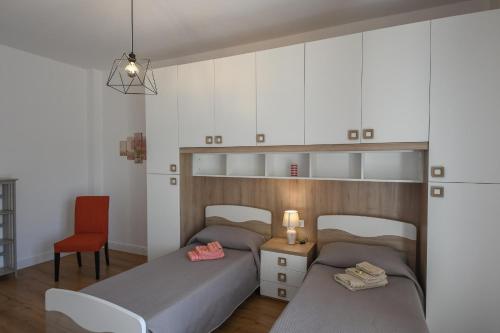a bedroom with two beds and a chair and cabinets at La Conchiglia in Savona
