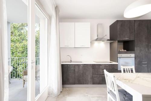 a kitchen with white cabinets and a table with chairs at Appartamenti Dama 1 in Bardolino