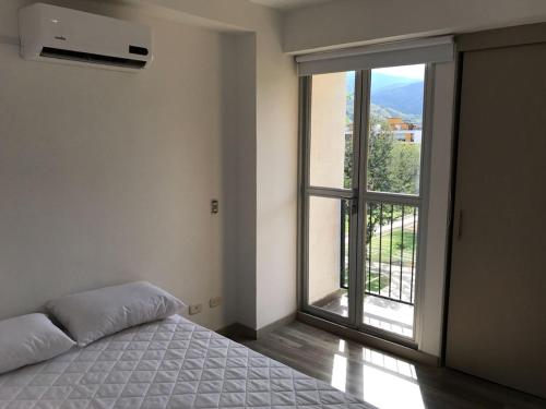 a bedroom with a bed and a large window at Apartasol de Lujo Santa Fe de Antioquia" in Santa Fe de Antioquia
