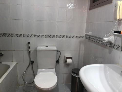 a white bathroom with a toilet and a sink at New Royal Mark Hotel Apartments in Dubai