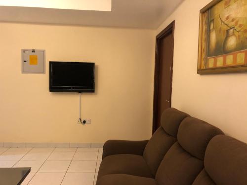 a living room with a couch and a flat screen tv at New Royal Mark Hotel Apartments in Dubai