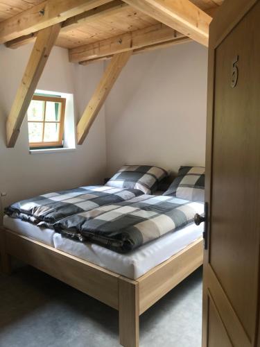 a bed in a bedroom with a wooden ceiling at Kameňácká myslivna in Moravany