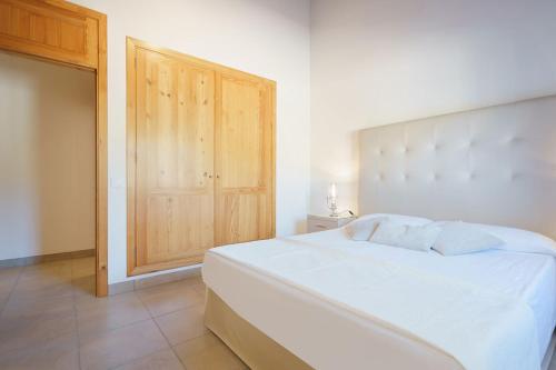 a bedroom with a white bed and a wooden cabinet at Sa Garriga in Ariany