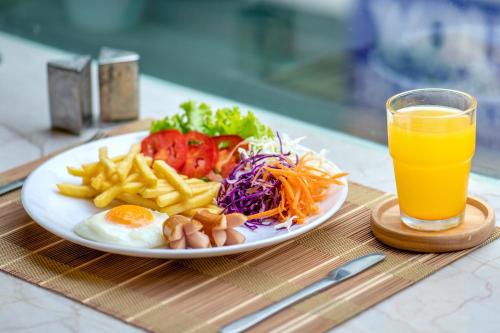 een bord met eieren en friet en een glas sinaasappelsap bij De Lavender Bangkok Hotel in Bangkok