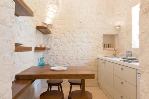 een keuken met een houten tafel en 2 krukken bij Trulli Terrarossa con Piscina in Martina Franca