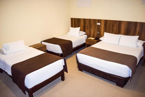a hotel room with two beds with white and brown sheets at Hotel Villa del Carmen in Arequipa