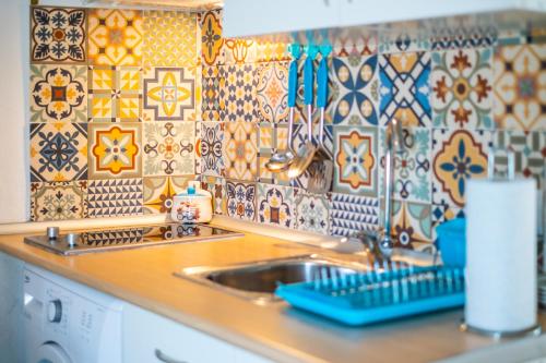 a kitchen with a sink and a tile wall at Casa Triana in Vejer de la Frontera