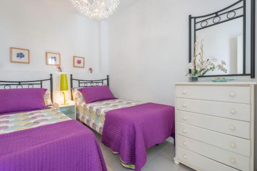 a bedroom with two beds and a dresser and a mirror at Apartamento Bateles in Conil de la Frontera